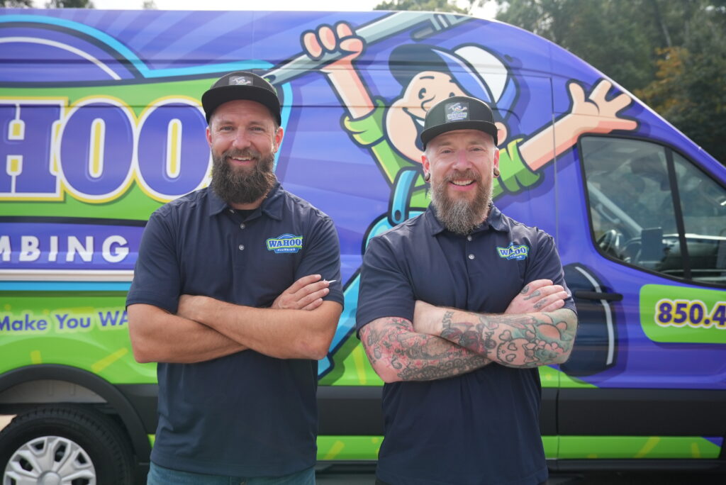 Professional plumbers posing in front of a Wahoo Plumbing company service vehicle.